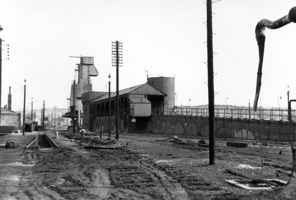 The coal stage and coaling plant at Grantham Loco viewed from the north east after removal of the track and prior to demolition. This would be early in 1964. The cabin described by Roy can clearly be seen, attached to the north end adjacent to the ramp. The pit on the left was associated with the former 'old shed'; the inside of its back wall can be seen on the extreme left. Photograph lent by Ken Willetts.