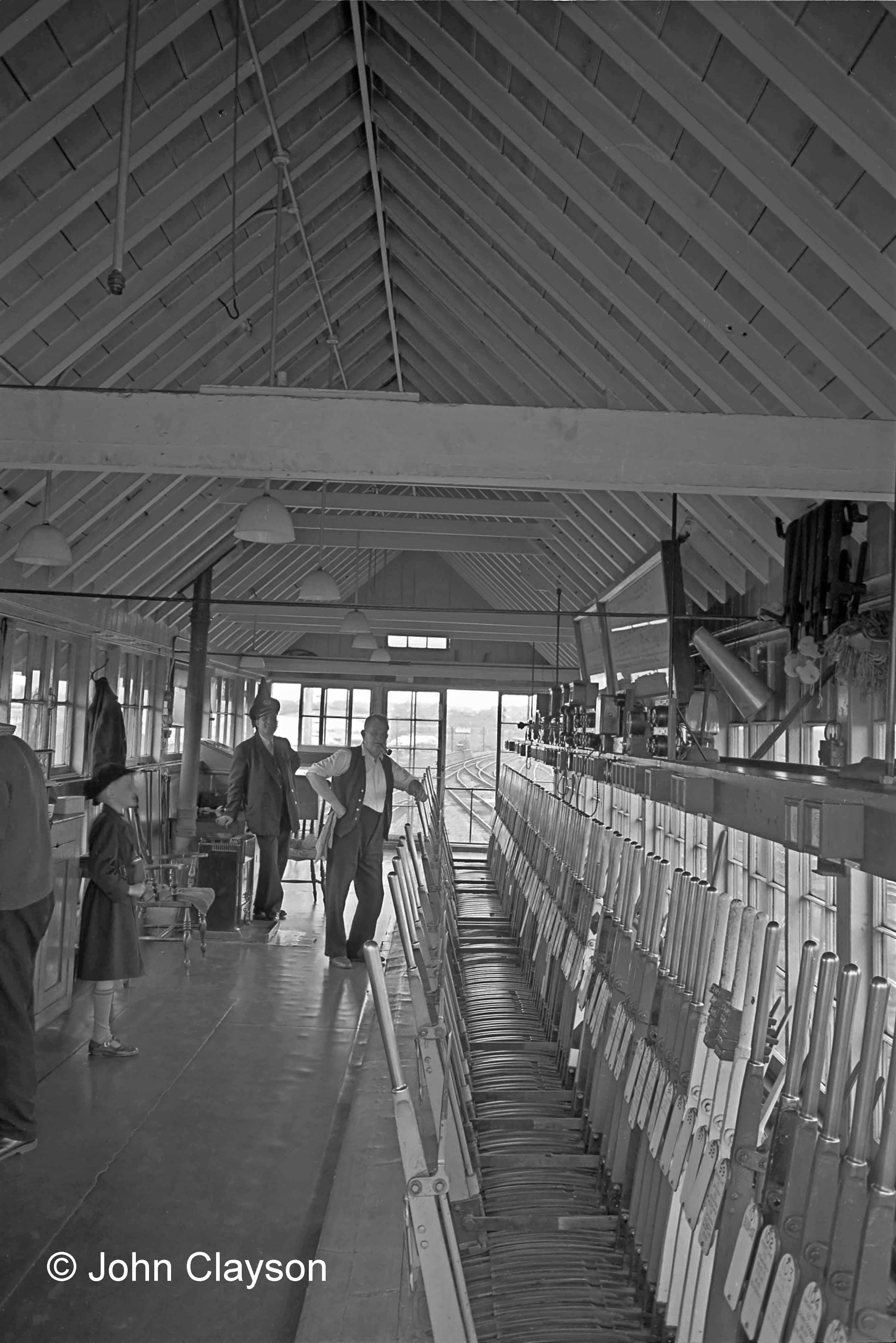 Grantham North signal box, looking north on 22nd August 1963. Hanging on the right is a row of point clamps, each with its padlock and key, for use in a situation where a turnout required to be secured immovable. There’s also a ‘loud hailer’ cone for conveying verbal instructions. A supply of lever collars - to be placed over a lever as a reminder of, for example, a stationary train which was to be protected - is kept on two of the four spare levers 95 to 98. On the left there’s a nine-year-old lad in a school cap who’s too excited by all this to keep still for the picture! At that stage in life I dreamed of being a railway signalman. Photograph by Cedric A. Clayson.