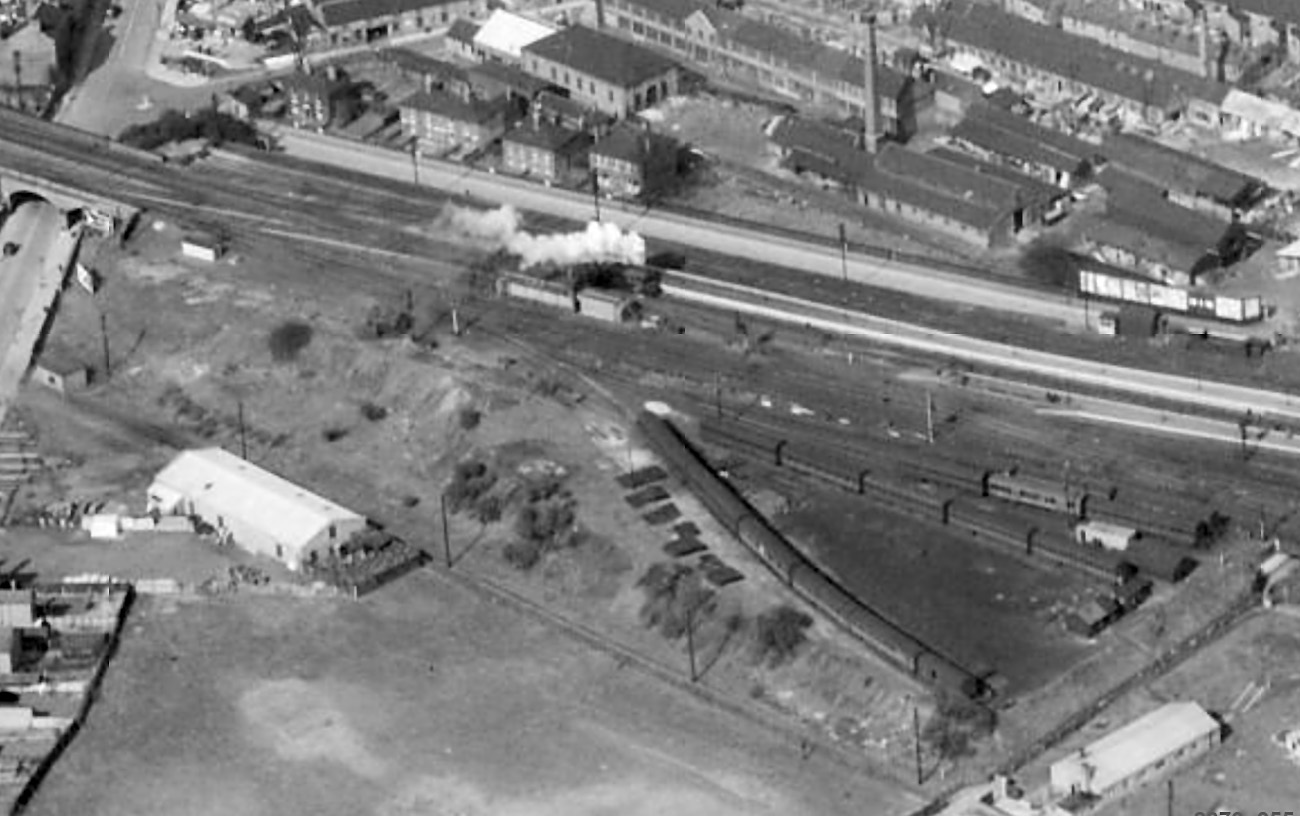 The box and its relay room are seen just above centre in this view taken on 19th April 1950. A locomotive steams past approaching the north end of the station, probably heading for the Yard Box engine siding to wait for a southbound train which it is due to take forward. The sidings at lower right, being used to store old coaches, are part of the Civil Engineer’s yard. Photograph from Britain From Above © English Heritage.