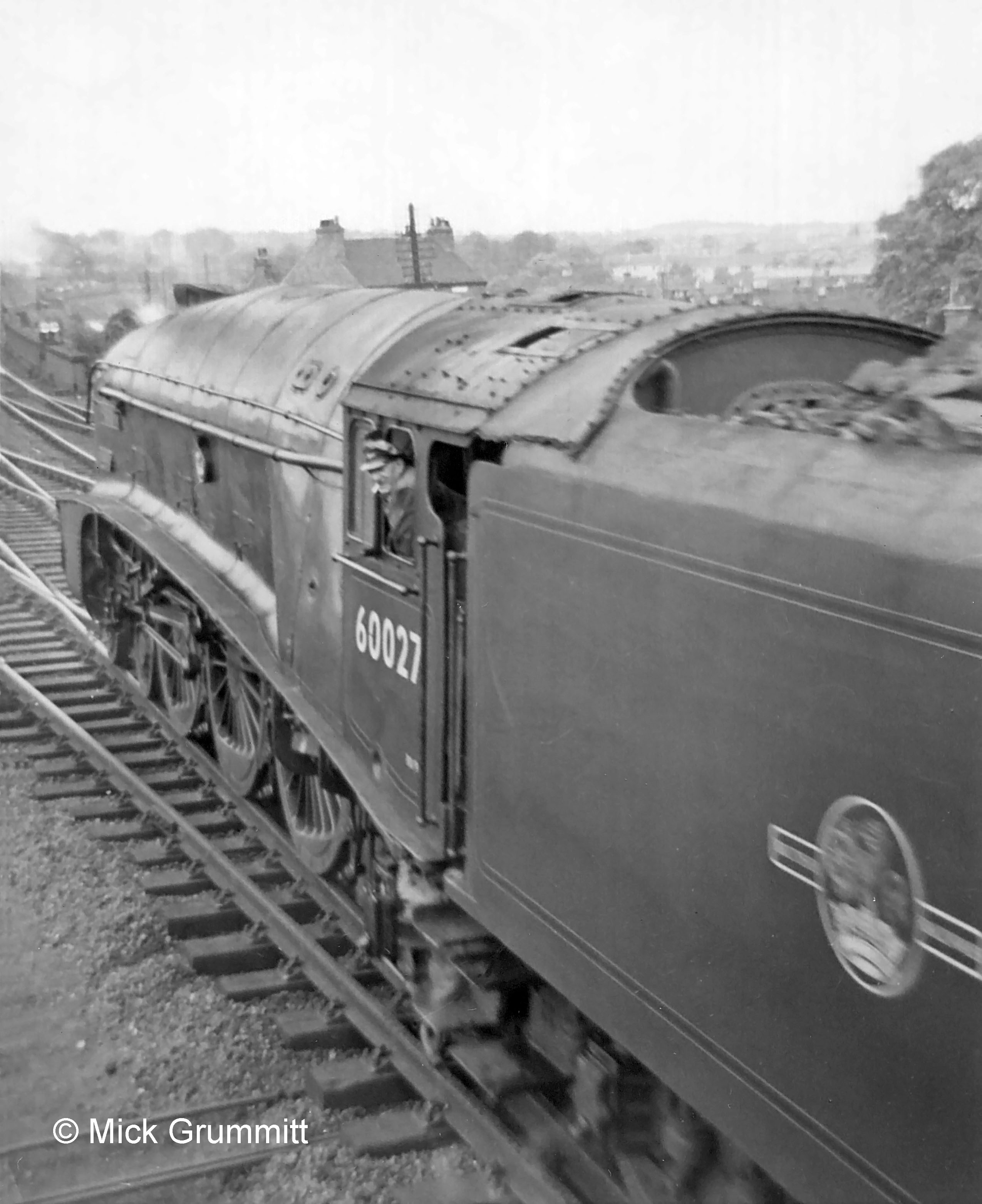 Passing the box windows with a departing northbound train on the Down Main line is No.60027 Merlin. Mick Grummitt who took this photograph recalls that this was the Down Elizabethan which was scheduled non-stop between London and Edinburgh, taking water at troughs en route. On this occasion the crew had stopped for water at Grantham because they had a ‘poor dip’ at Langley troughs near Stevenage (probably because the troughs hadn’t had time to refill fully after the previous train) and the following troughs at Werrington, north of Peterborough, were out of use for maintenance work. They didn't want to risk the next troughs, at Muskham near Newark, being low as well. Mick remembers that the unexpected 'arrival' of a passenger train at the platform when none was due caused a bit of a panic among the station staff! Photograph by Mick Grummitt, relief Telegraph Lad at Grantham North 1959-62.