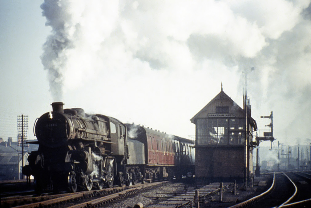 This service for Lincoln, departing on Monday 25th February 1963 at at around 2.45pm and hauled by 4MT locomotive No.43146, has just left the Western platform and joined the Down Main line. We know this because the Western platform to Down Main line starting signal can just be glimpsed in the ‘off’ position on the right. At Barkston South Junction the train will turn off the main line towards its destination. Passenger trains to and from Nottingham, departing from and arriving at the western side of the station, passed the box using the line on the right. In the foreground, leading from the base of the box, is an array of steel point rodding carried on rollers. Each rod operates a different point mechanism from its nominated lever in the box. Photograph taken by Noel Ingram, used with permission from Steam World.