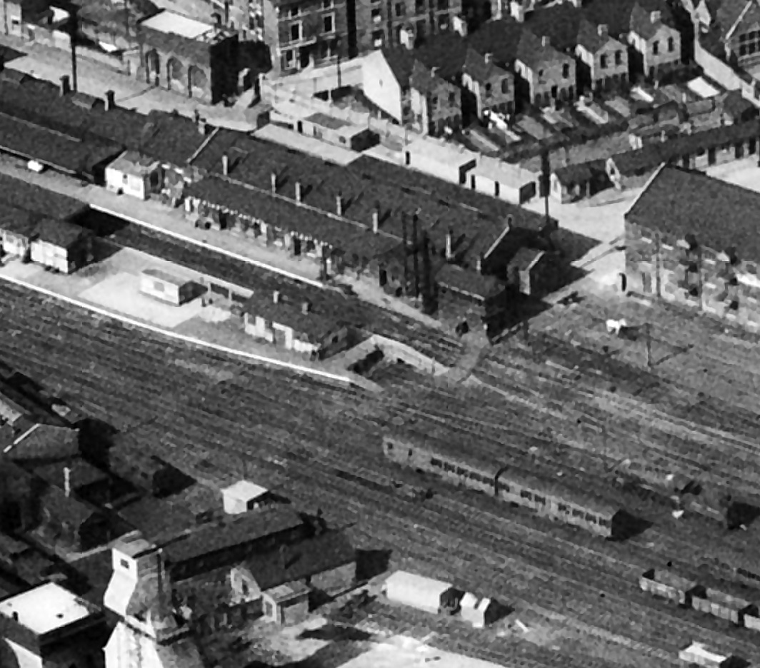 Grantham Yard signal box is at the platform end, slightly to the right of centre in this photograph, which was taken on 19th April 1950. The station platforms and buildings lie to its left, with the station water tower near the top left corner, across Station Road. At lower left are the Loco Department offices and workshops, with the top of the shed water tower and the coaling plant at the bottom left corner. Photograph from Britain From Above © English Heritage.