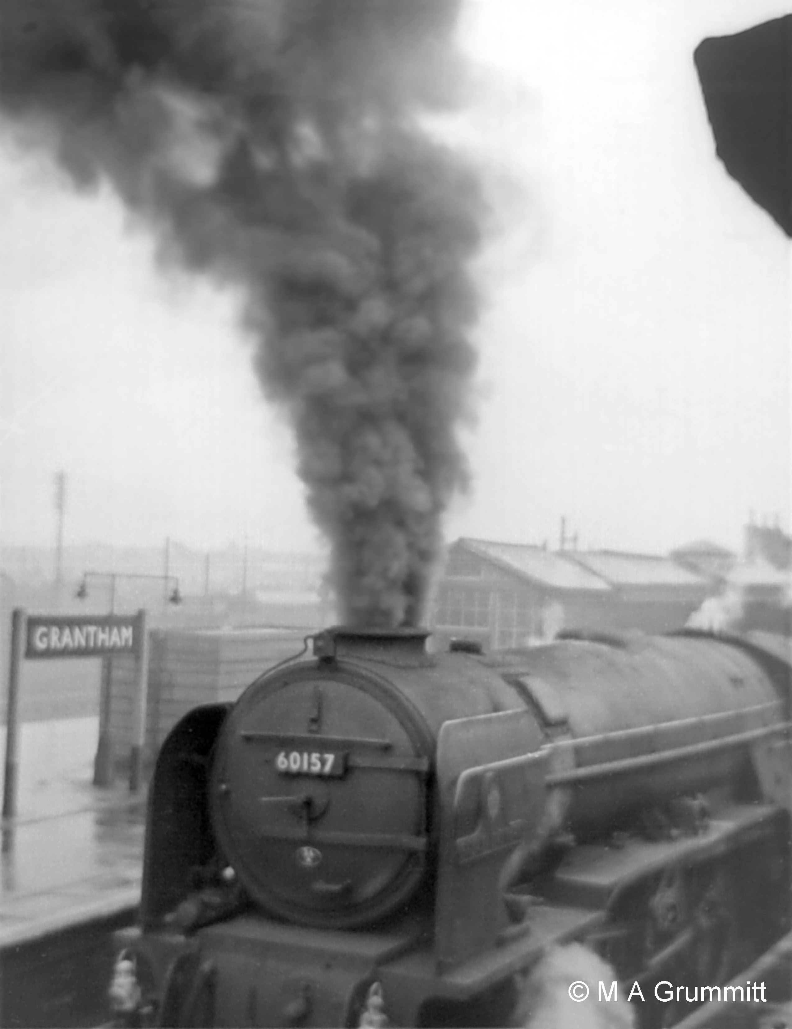 In some weather conditions signalling staff, in their elevated position at the end of a station platform, could be wreathed in locomotive smoke. The fireman of A1 No. 60157 Great Eastern has prepared for the 5-mile ascent to Stoke Tunnel from a standing start at Grantham by adding fresh coal to the fire. Had the wind been from the north west, the Yard Box could have been enveloped in smoke for several minutes . Photograph by Mick Grummitt.