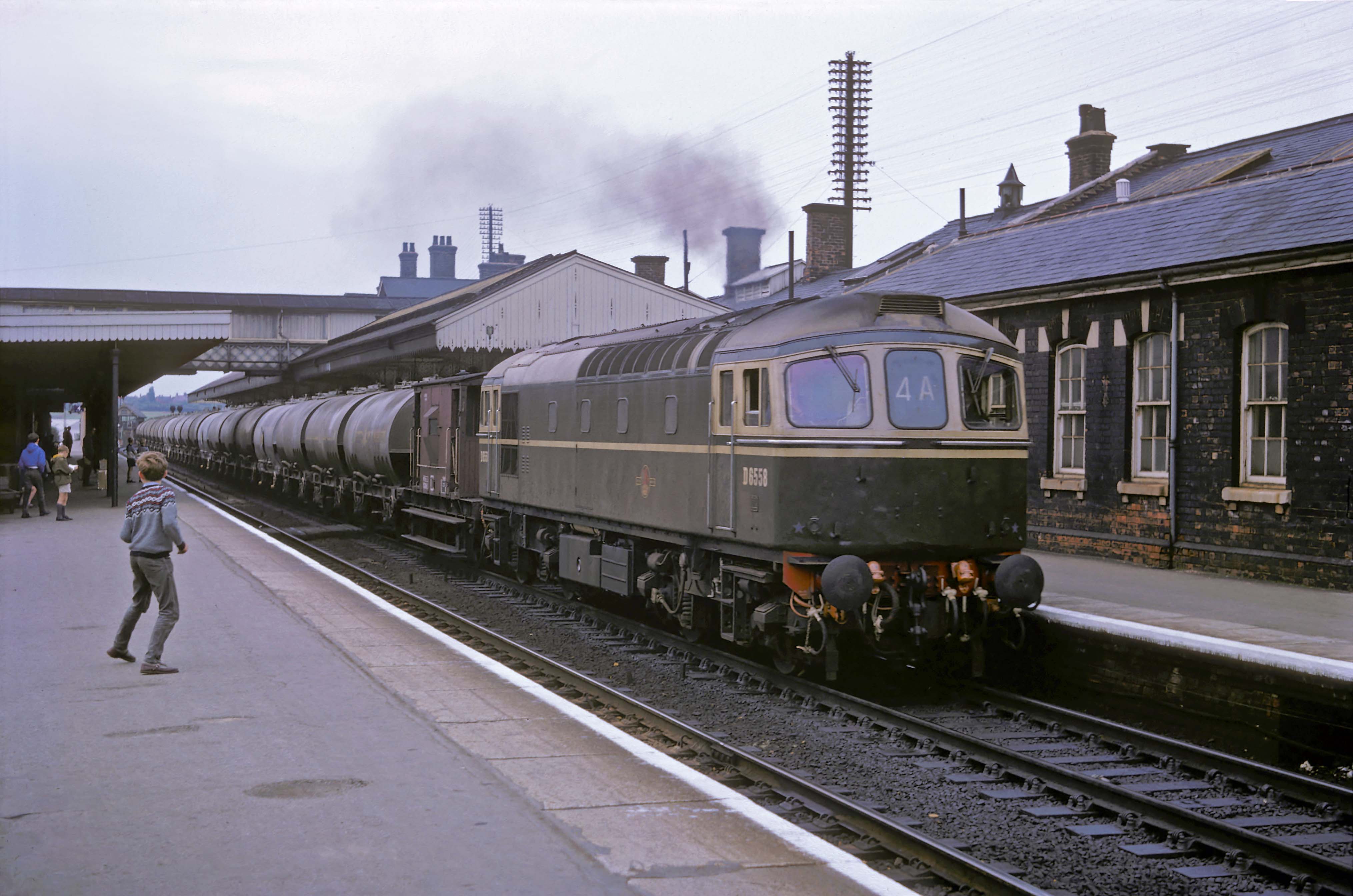 In August or September 1965 a southbound train of empty cement wagons is hauled by BRCW Type 3 (later Class 33) diesel electric locomotive No. D6558, based on the Southern Region. The cement train was always eagerly anticipated among spotters because these locomotives were not otherwise seen in the Midlands. Photograph by Cedric A. Clayson, © John Clayson