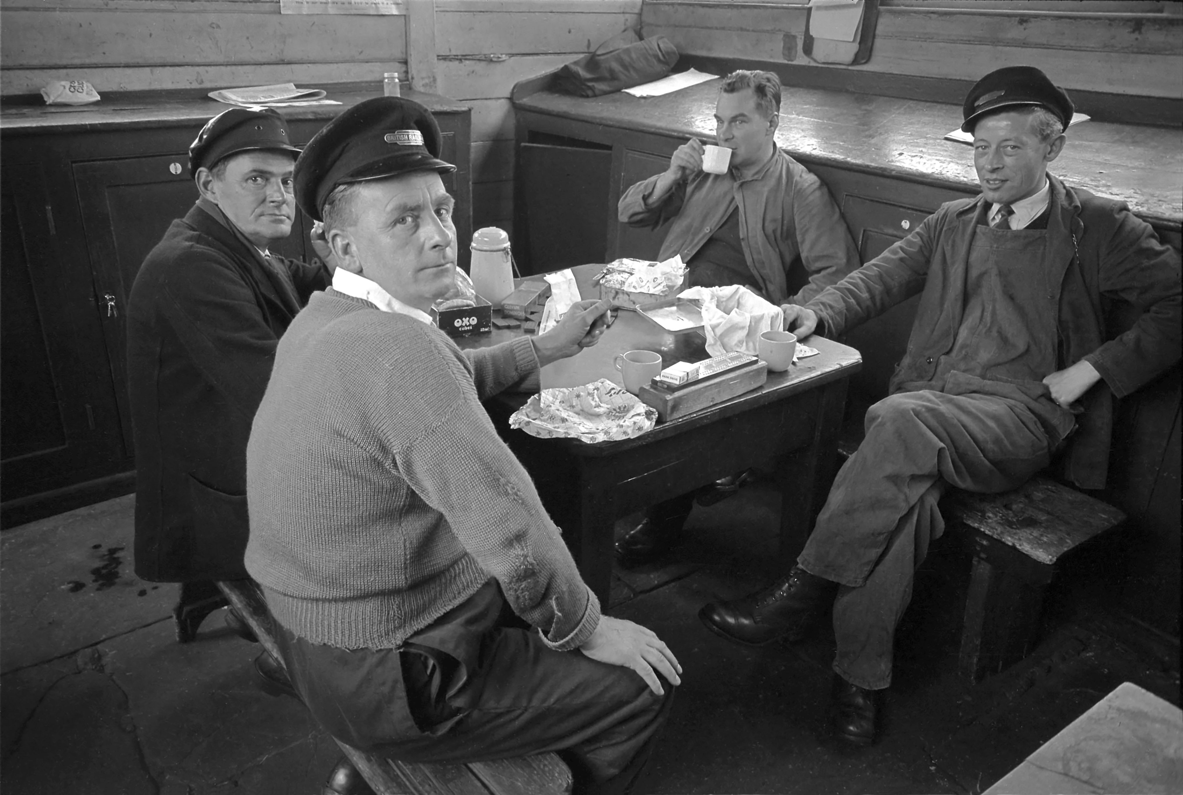 Taking a break in the Passenger Shunters' cabin at the south end of the ‘down’ platform on 15th August 1963. On the table, among the lunch boxes and tea cans, are a cribbage board and a set of dominoes. Left to right: Driver Albert Bottomley, Passenger Shunter Gilbert Needham, Driver Ted Matsell and Passenger Shunter Dennis (Dick) Knight. Passenger Shunters assisted with locomotive changes and arranged the coaches in the carriage sidings at the south end of the station into train formations. Photograph by Cedric A. Clayson, © John Clayson