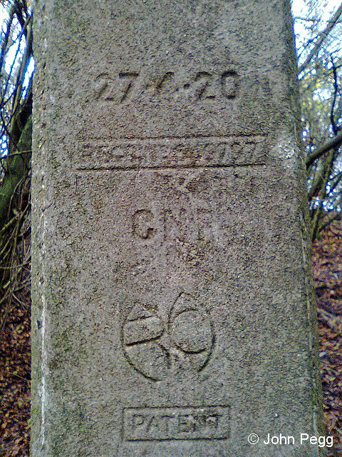 Signal post inscription, cast into the concrete. Coming up for 100 years old. The monogram is 'MRC' standing for 'Marriott Reinforced Concrete'. William Marriott was the manager of the Midland & Great Northern Railway's workshops at Melton Constable in Norfolk, where he estabished a concrete works for producing railway equipment normally made from timber. A great number of signal posts were produced at Melton Constable for the M&GN, GCR, MR and GNR. Ellis & Sons of Leicester were licensed to produce more. The materials were cement, sand and small gravel aggregate, the latter two materials quarried locally at Kelling Heath and Holt. The first post was erected in 1915, and concrete posts were produced right up to the time the Melton Works were closed in December 1936. . (Nigel Digby on 'The Signal Box Forum', 31 Oct 2013)